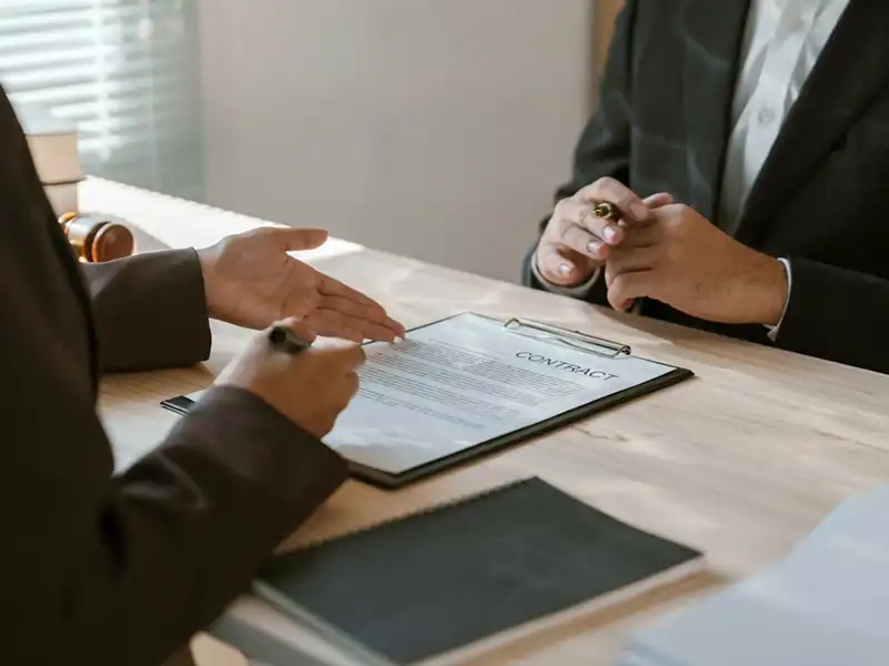 An image of two people inspecting a contract document prior to signature.